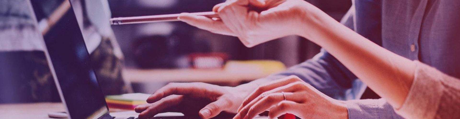 Osoba wskazuje ołówkiem na ekran laptopa