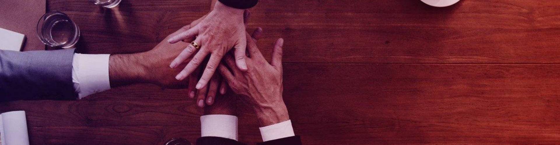 Biznesmeni łączą ręce nad stołem